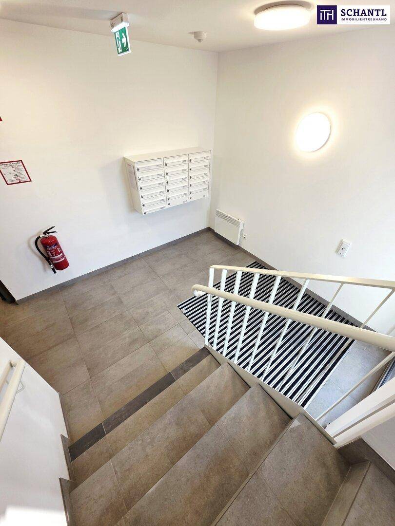 Treppenhaus mit Fliesenboden, Briefkästen und einem Feuerlöscher an der Wand.