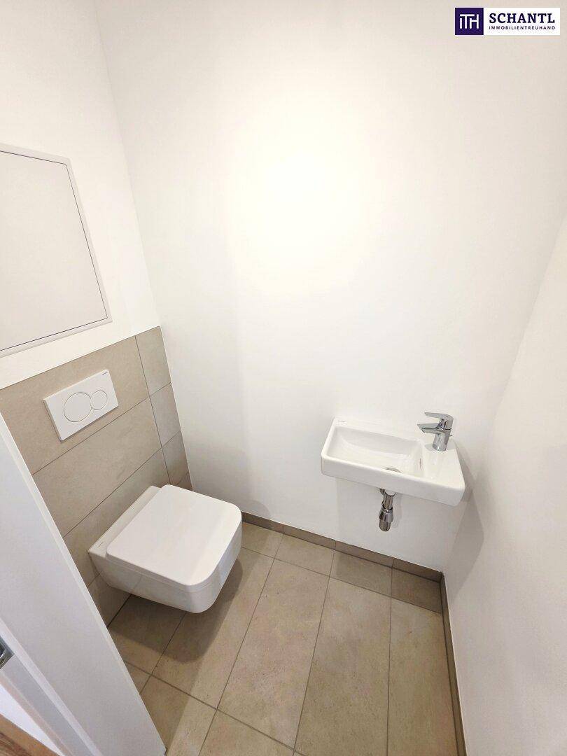 Kleines Gäste-WC mit wandhängender Toilette und modernem Waschbecken in hellen Fliesen.