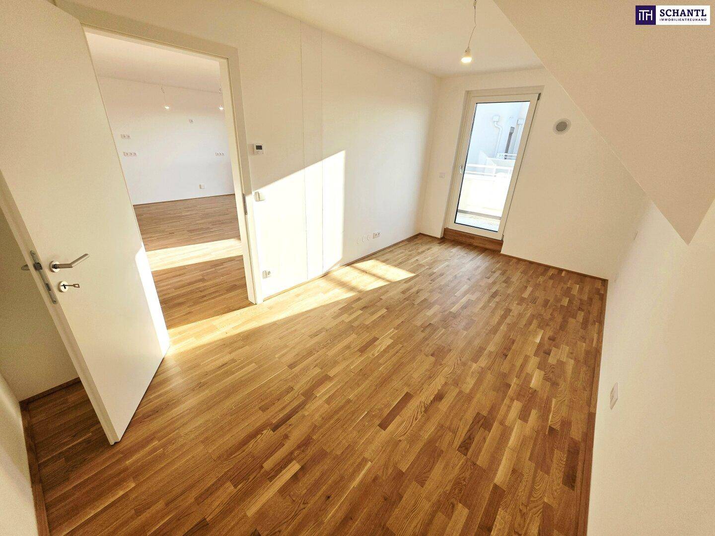 Helles Zimmer mit Holzboden und Zugang zu einem Balkon, ideal als Schlaf- oder Arbeitszimmer.