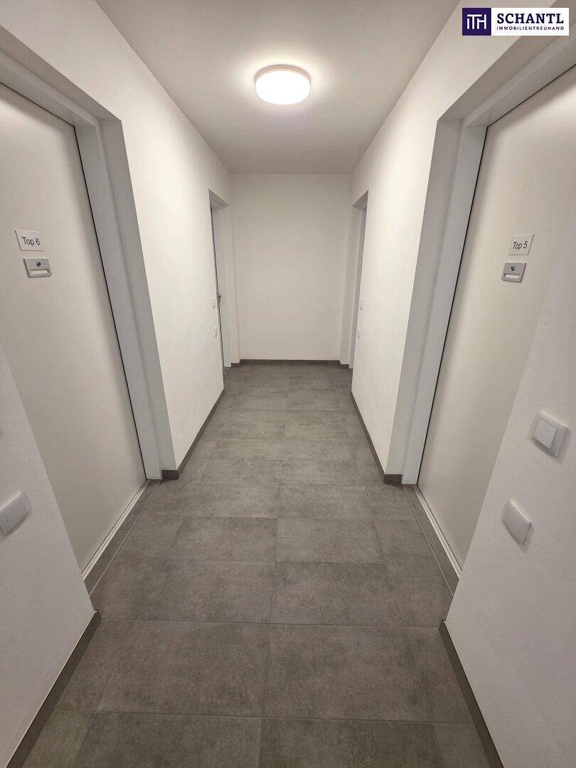 Heller Flur mit Fliesenboden und mehreren Wohnungstüren, der zu den einzelnen Einheiten führt.