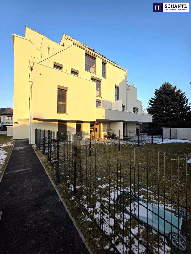 Moderne Wohnanlage mit gepflegtem Gartenbereich und Zaun, teilweise mit Schnee bedeckt.