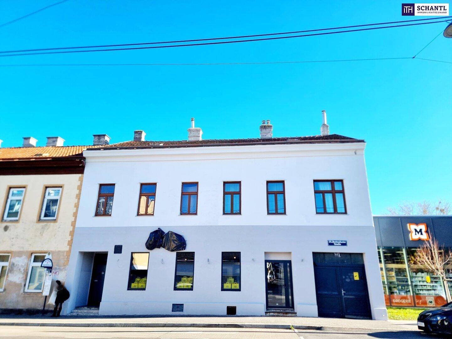 Historisches Gebäude mit weißer und grauer Fassade an einer belebten Straße.