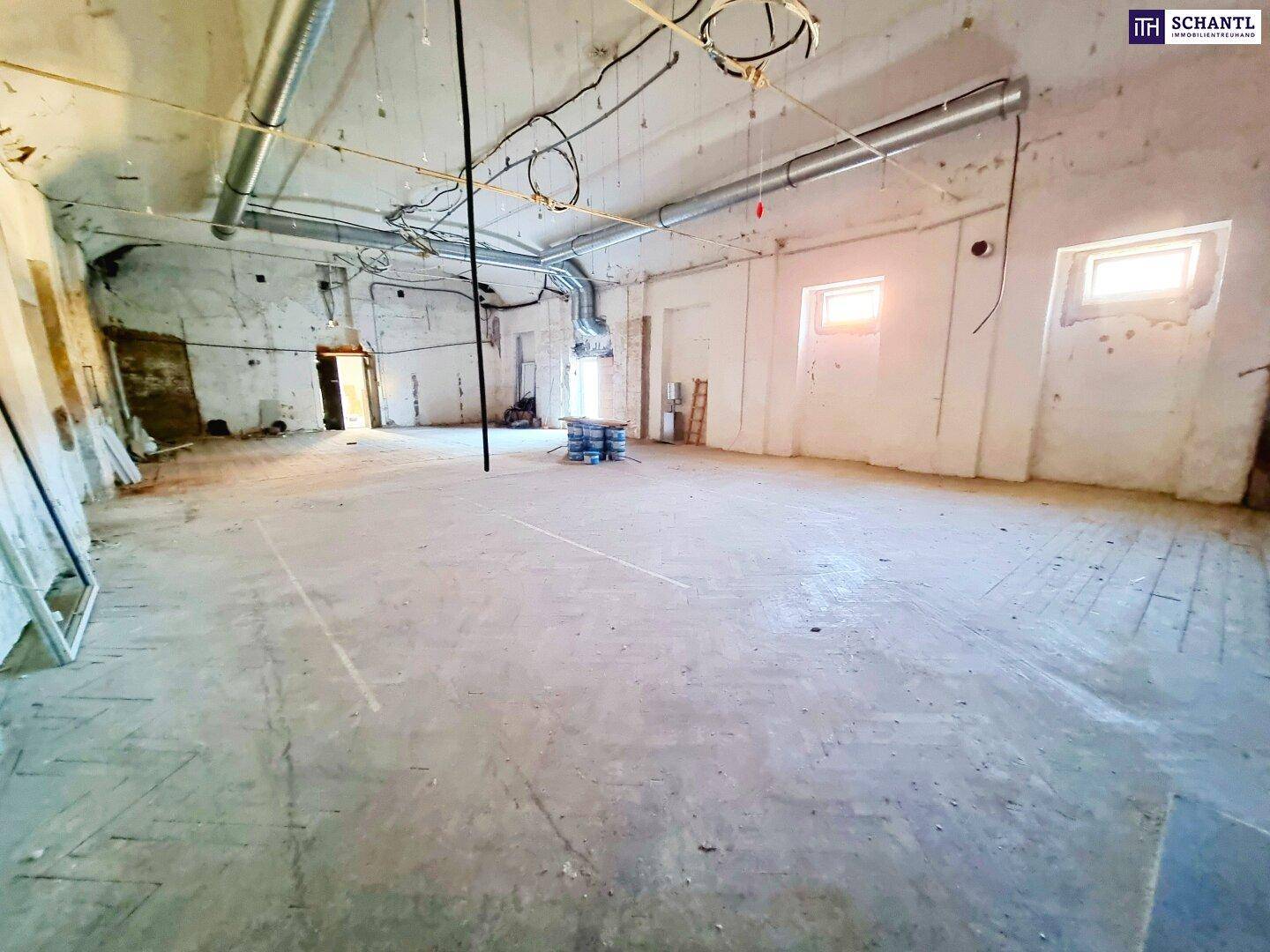Weiter, leerer Raum mit Betonboden und sichtbaren Lüftungsrohren, ideal für Umbau.