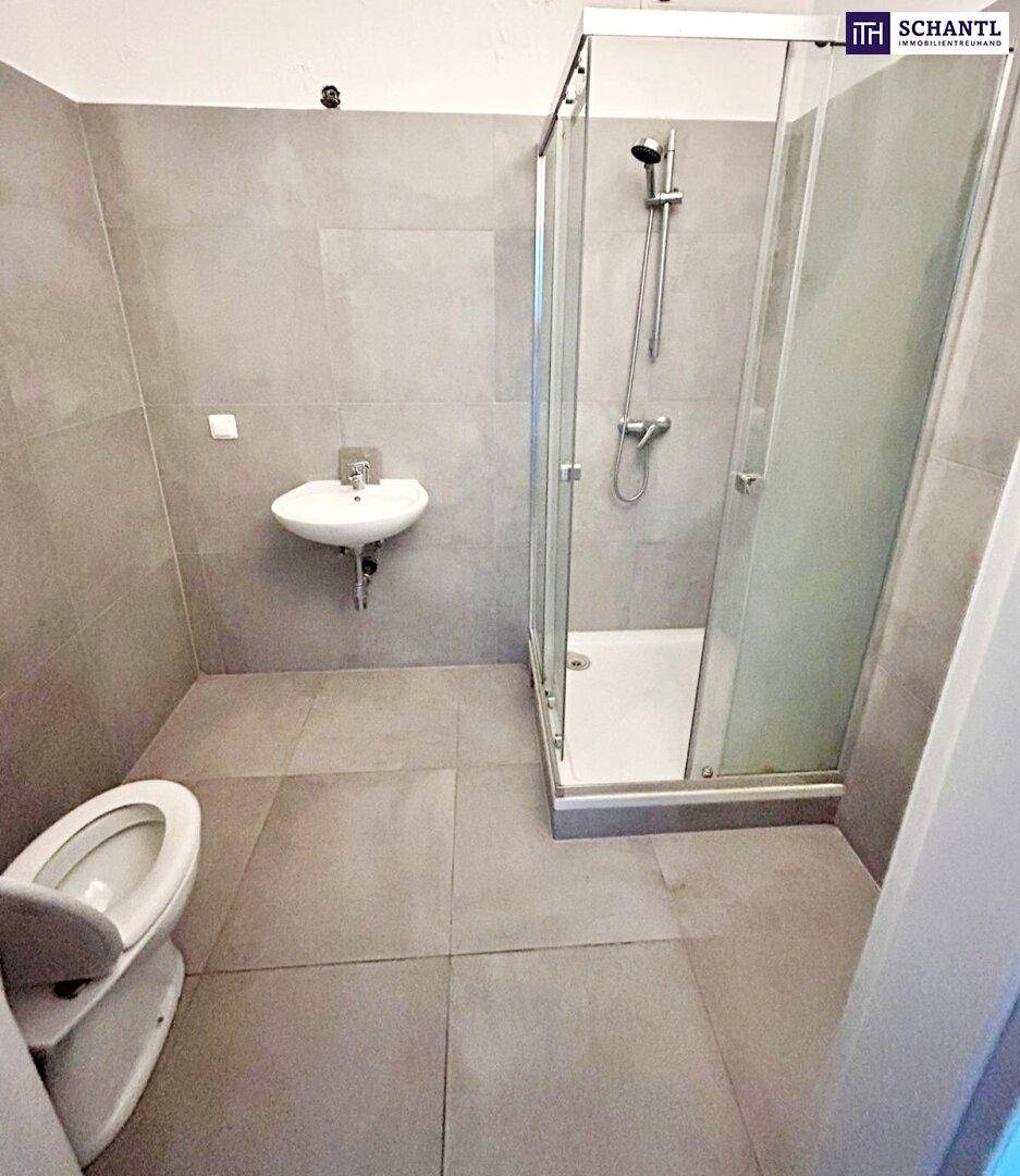 Modernes Badezimmer mit grauen Fliesen, Duschkabine und wandhängendem WC.