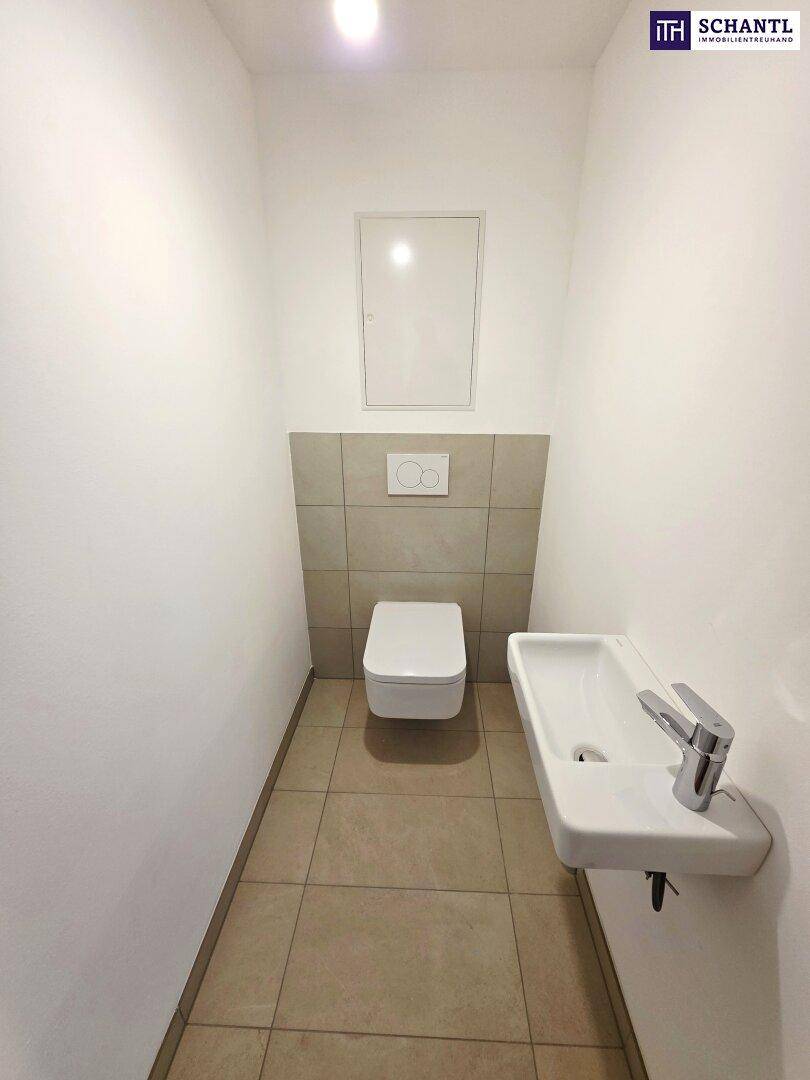 Modernes Gäste-WC mit Wand-WC, kleinem Waschbecken und Fliesenboden.