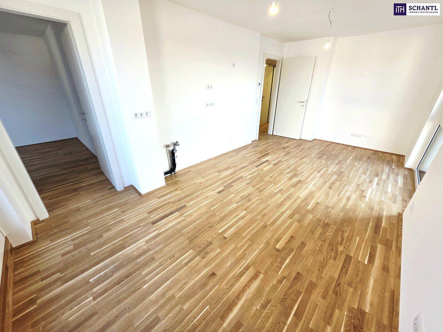 Heller, leerer Raum mit neuem Holzboden und weißen Wänden, bereit für die Einrichtung.