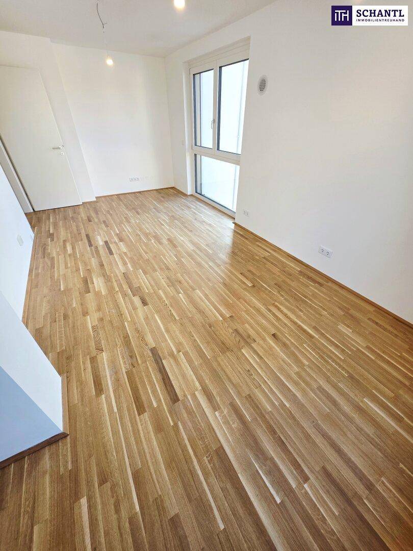Lichtdurchfluteter, leerer Raum mit Holzboden und großem Fenster, ideal für ein Schlafzimmer oder Büro.