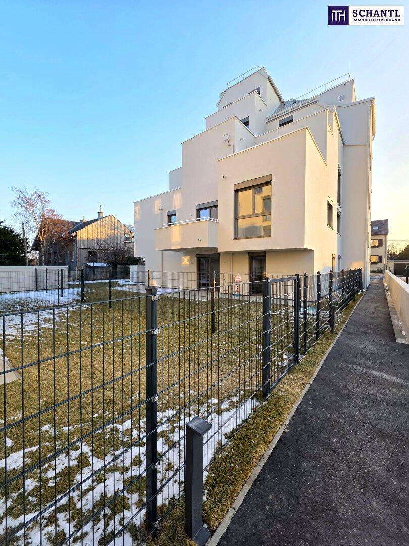 Moderne Wohnanlage mit klaren Linien und einem gepflegten Außenbereich mit Zaun und Gehweg.