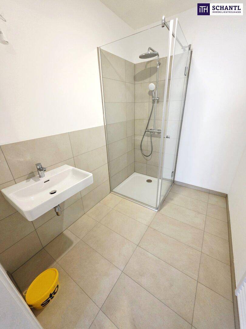 Modernes Badezimmer mit Duschkabine, Waschbecken und hellen Fliesen.