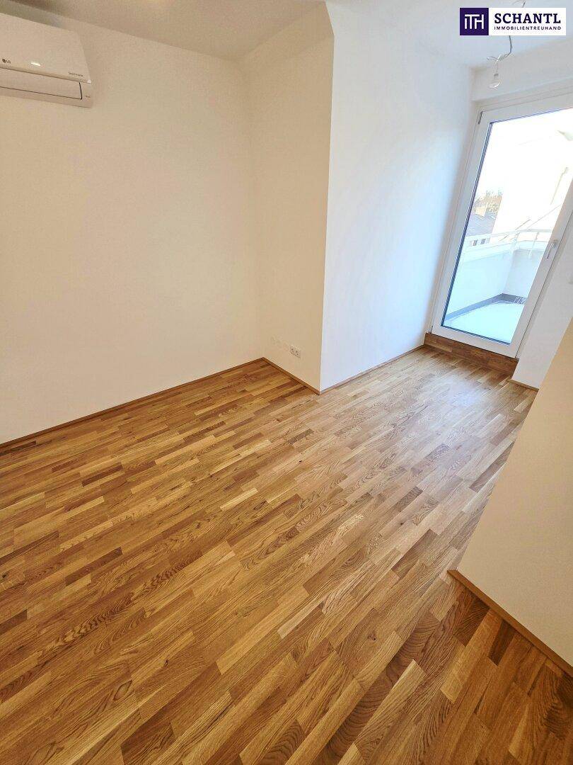 Helles Zimmer mit Parkettboden und großem Fenster, das viel Tageslicht hereinlässt.
