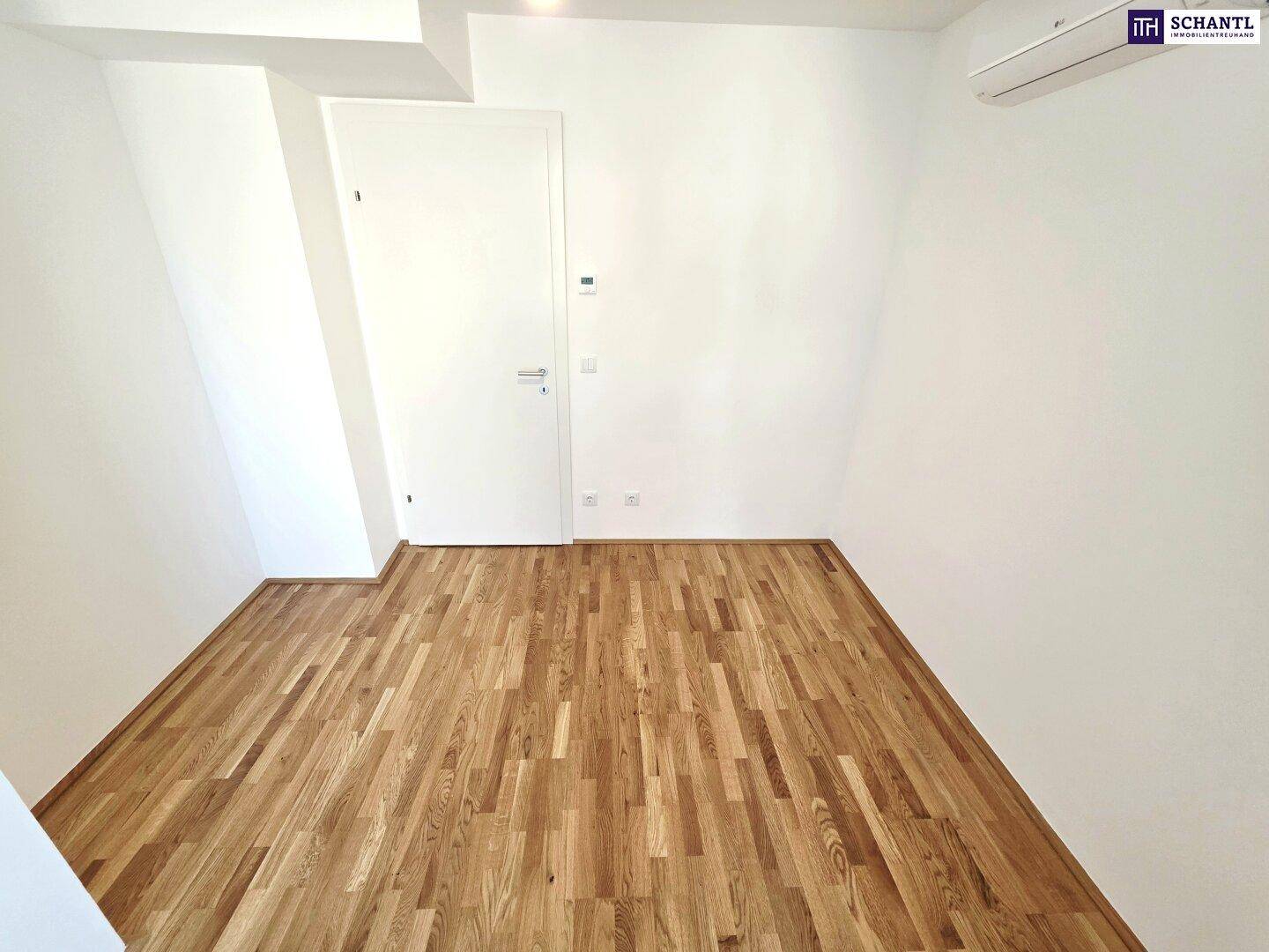 Leeres Zimmer mit Parkettboden, weißen Wänden und Dachschrägen, bereit zur individuellen Gestaltung.