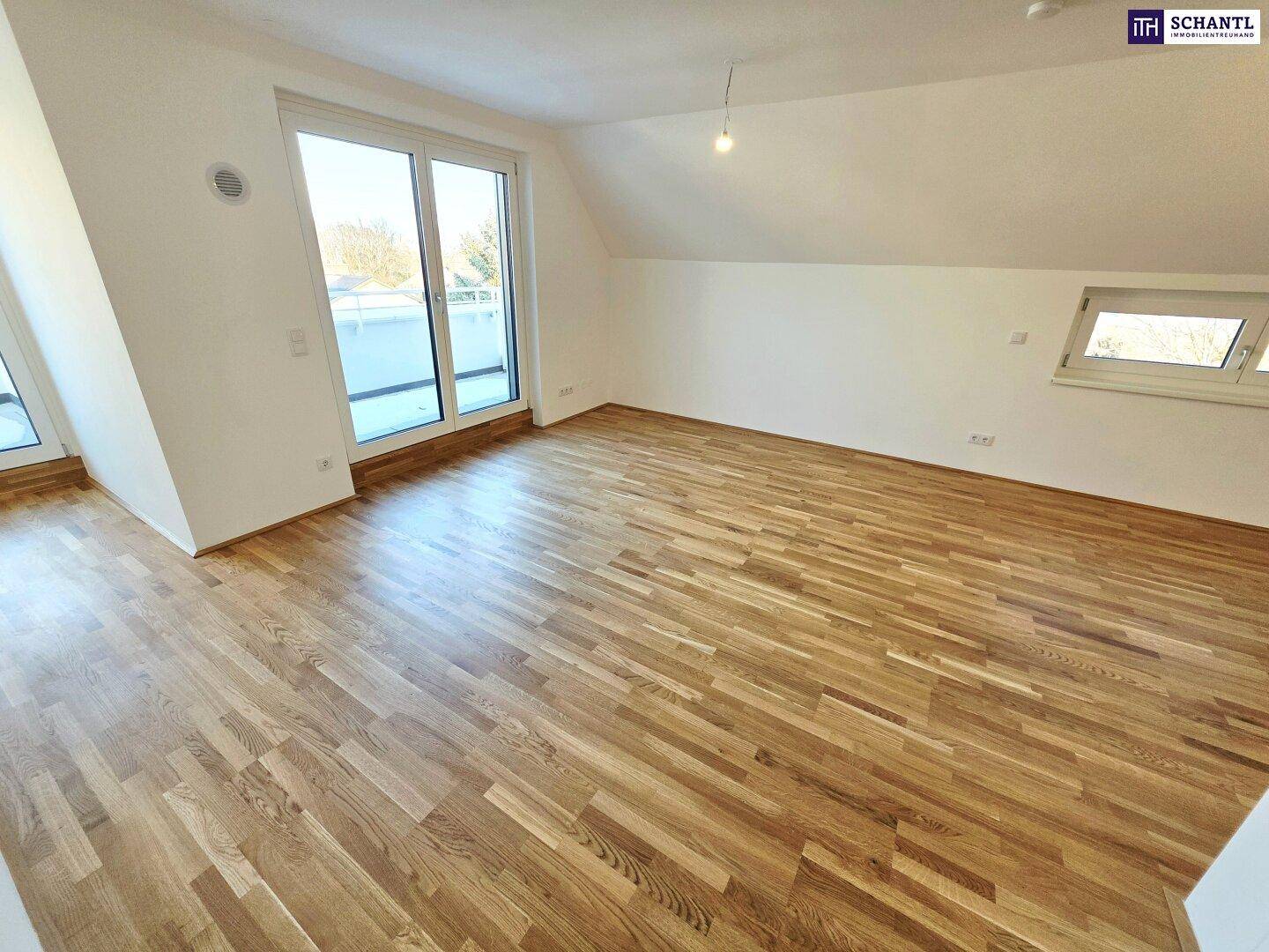 Heller Wohnraum mit Parkettboden, großen Fenstern und Zugang zum Außenbereich.