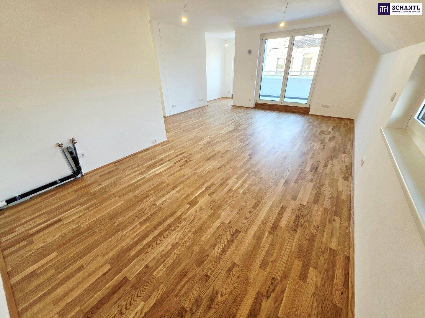Heller Wohnbereich mit Parkettboden und Zugang zu einem Balkon oder einer Terrasse.