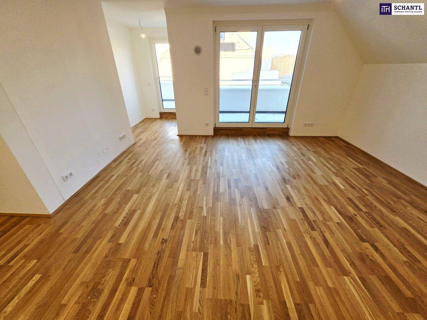 Großzügiger Wohnraum mit Holzboden und viel Tageslicht durch die breite Fensterfront.