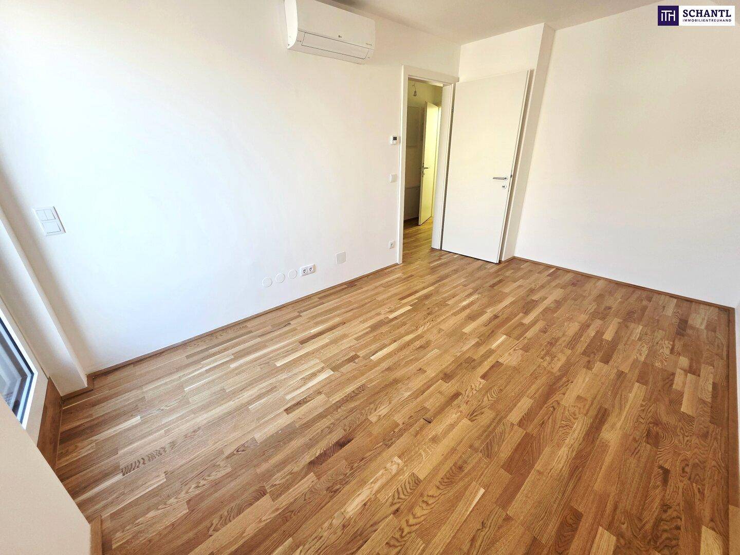 Unmöbliertes Zimmer mit Parkettboden, weißen Wänden und Klimaanlage, bereit zur Gestaltung.