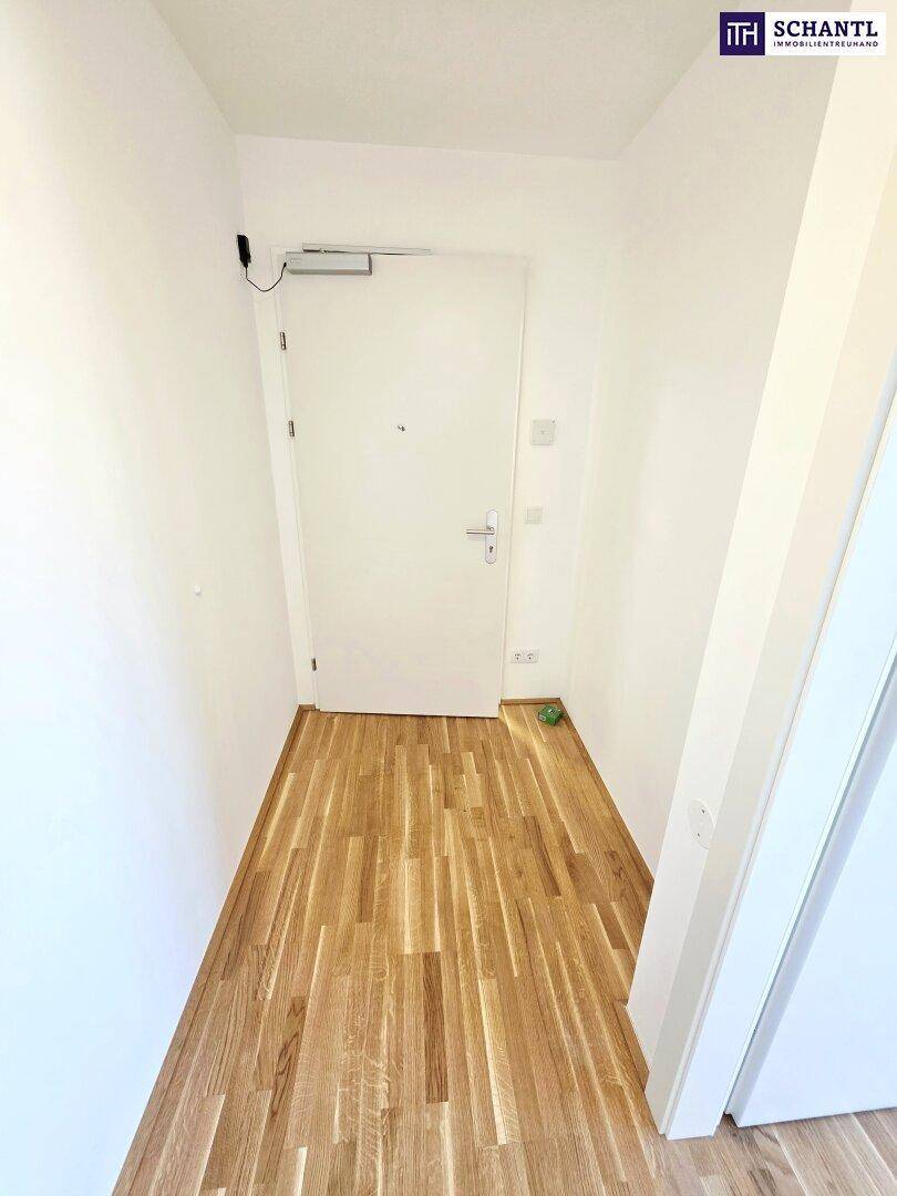 Eingangsbereich mit Holzboden und weißer Tür, der in die Wohnung führt.