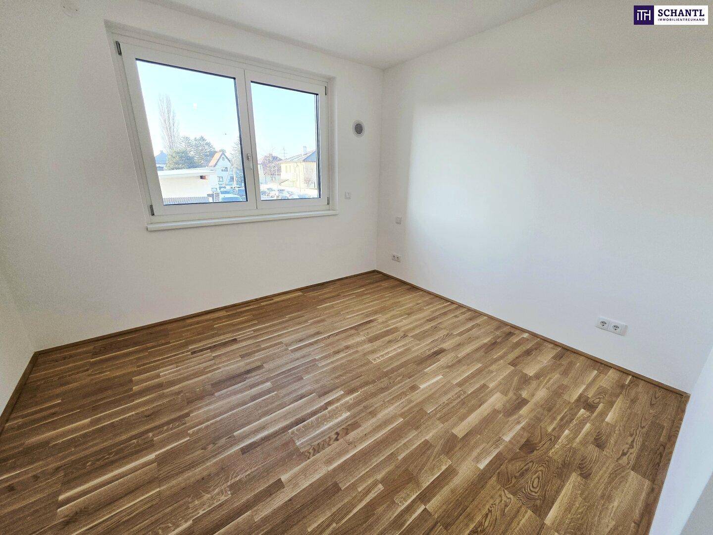 Freundliches Zimmer mit Parkettboden und großem Fenster, das eine weite Aussicht bietet.