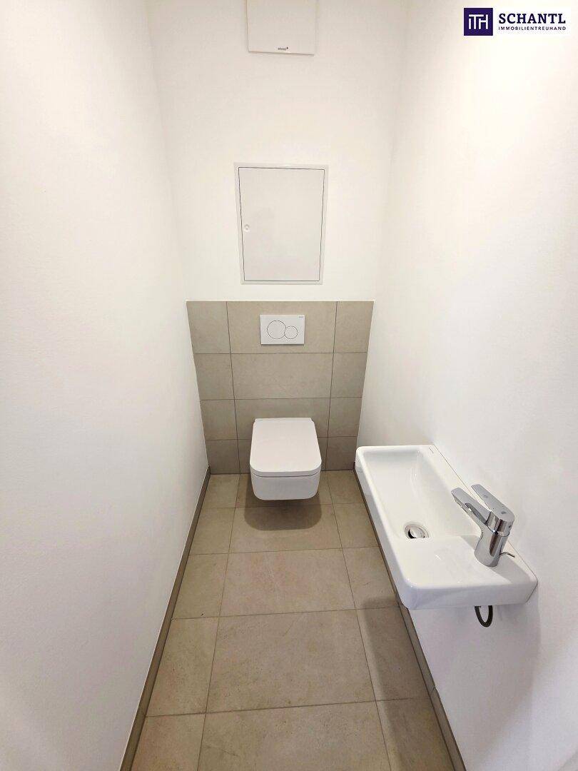 Separates Gäste-WC mit wandhängender Toilette und kleinem Waschbecken.