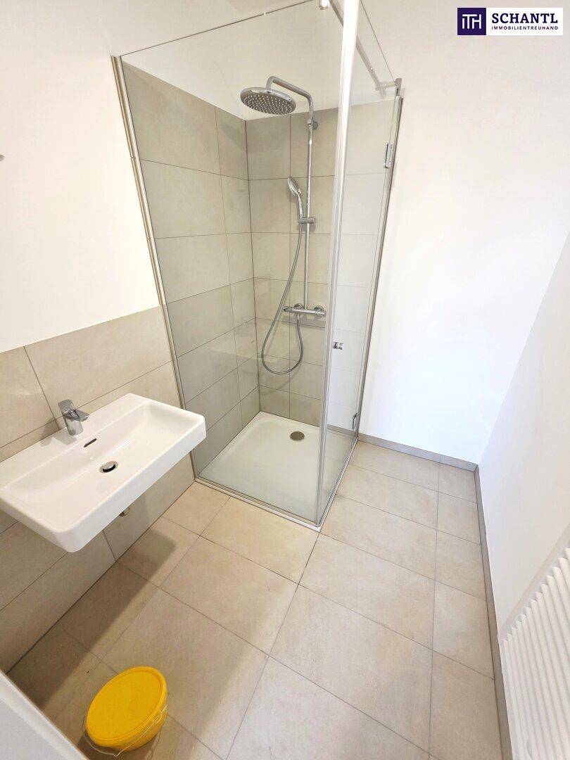 Modernes Badezimmer mit Duschkabine, Waschbecken und hellen Fliesen.