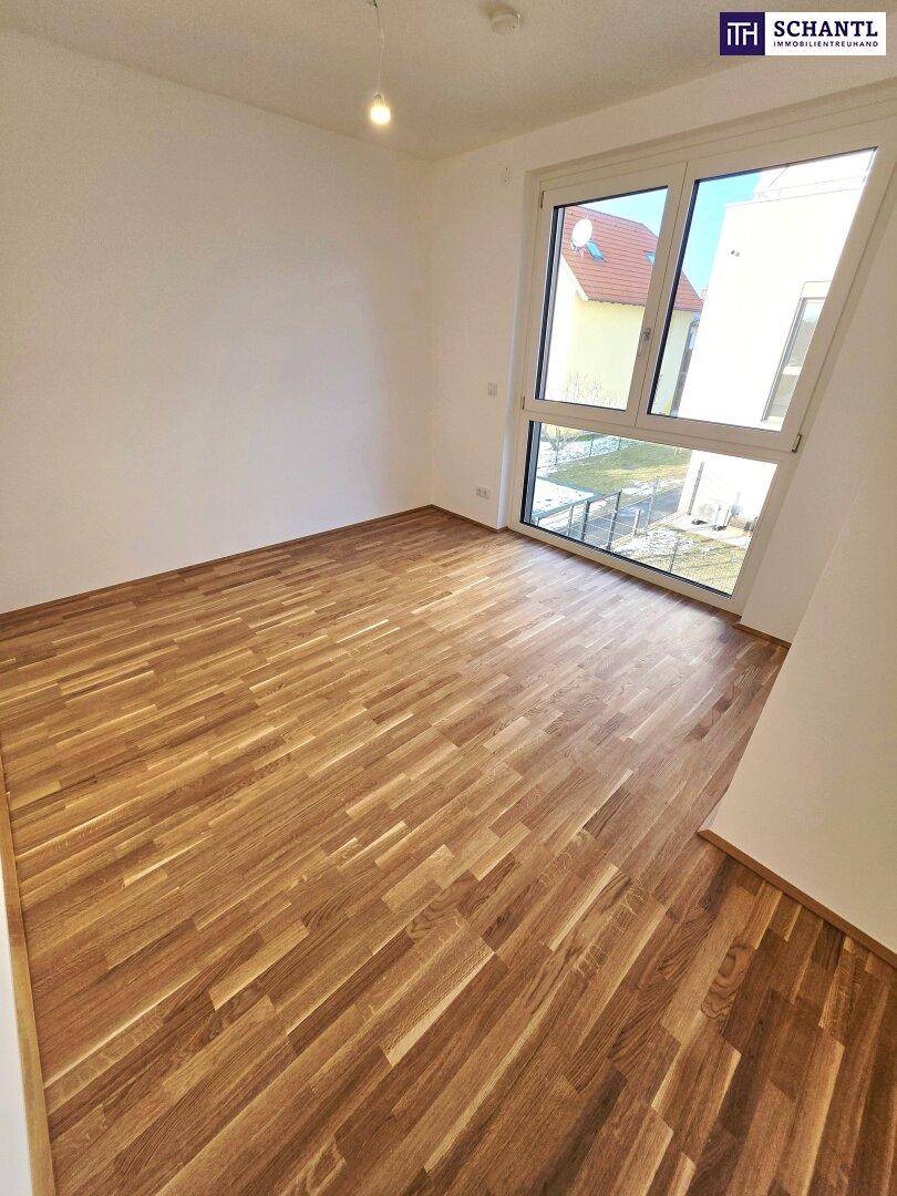 Geräumiges Wohnzimmer mit großen Fenstern und hellem Parkettboden, bereit zur Einrichtung.