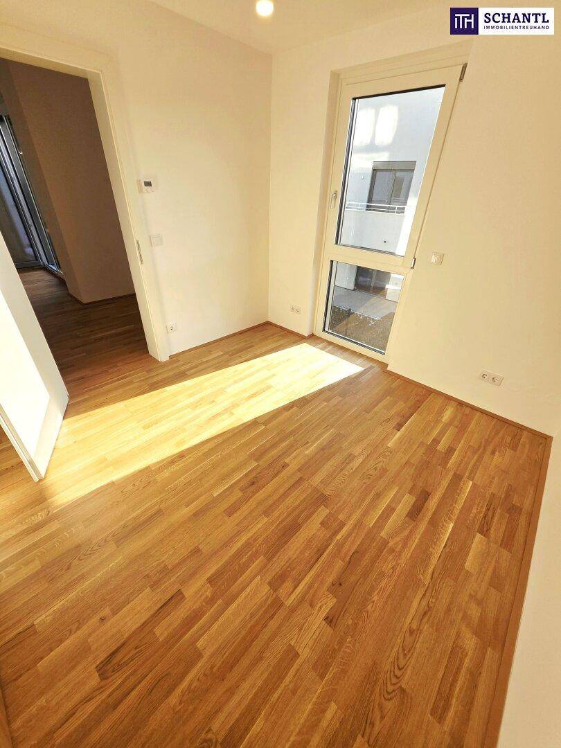 Helles Zimmer mit Parkettboden und großem Fenster, das viel Tageslicht hereinlässt.