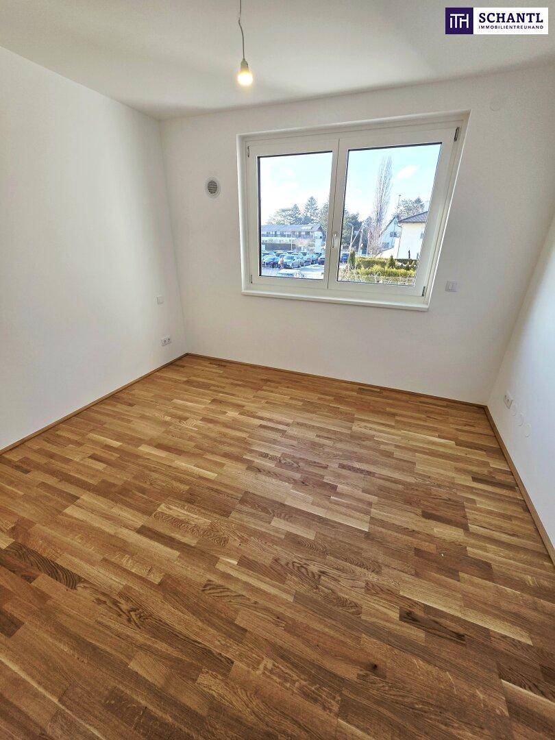 Helles Zimmer mit Parkettboden und großem Fenster, das einen weiten Blick ermöglicht.