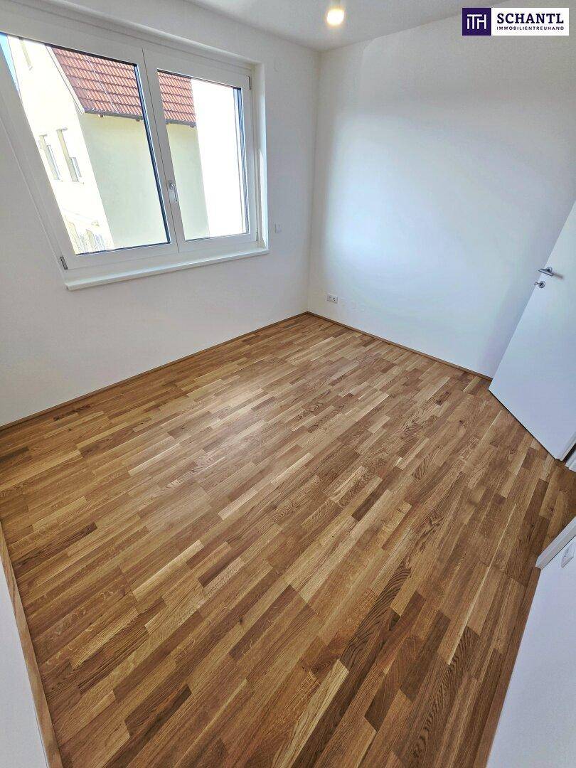 Helles Zimmer mit Parkettboden und Fenster, das viel Tageslicht in den Raum bringt.