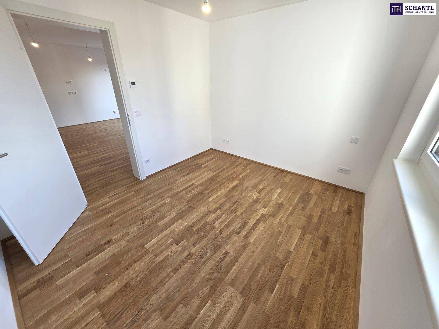 Helles Zimmer mit Parkettboden und Fenster, das viel Tageslicht in den Raum bringt.