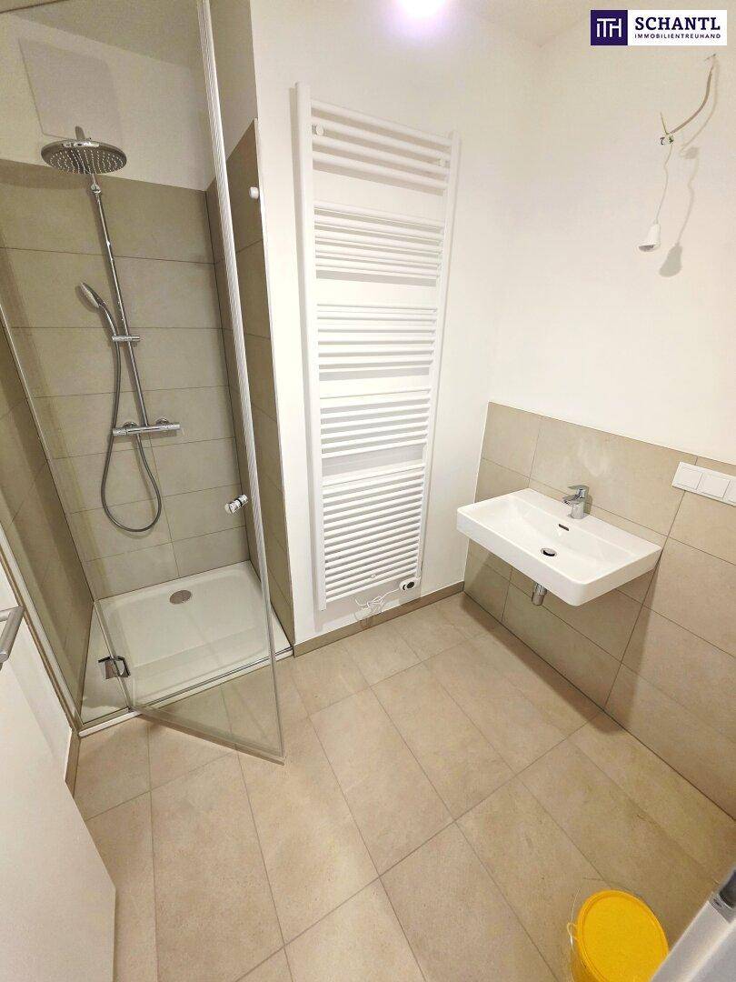 Modernes Badezimmer mit Duschkabine, Waschbecken und beheiztem Handtuchhalter.