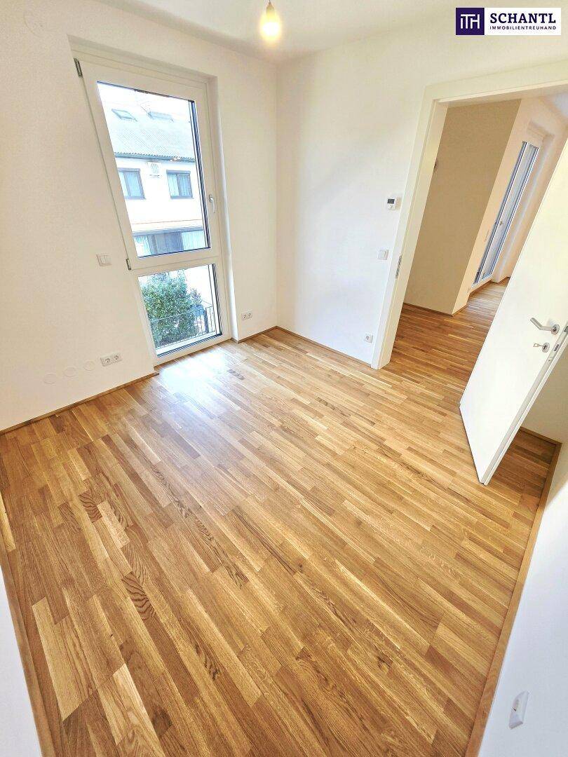 Helles Zimmer mit Parkettboden und großem Fenster, ideal als Schlaf- oder Arbeitszimmer.