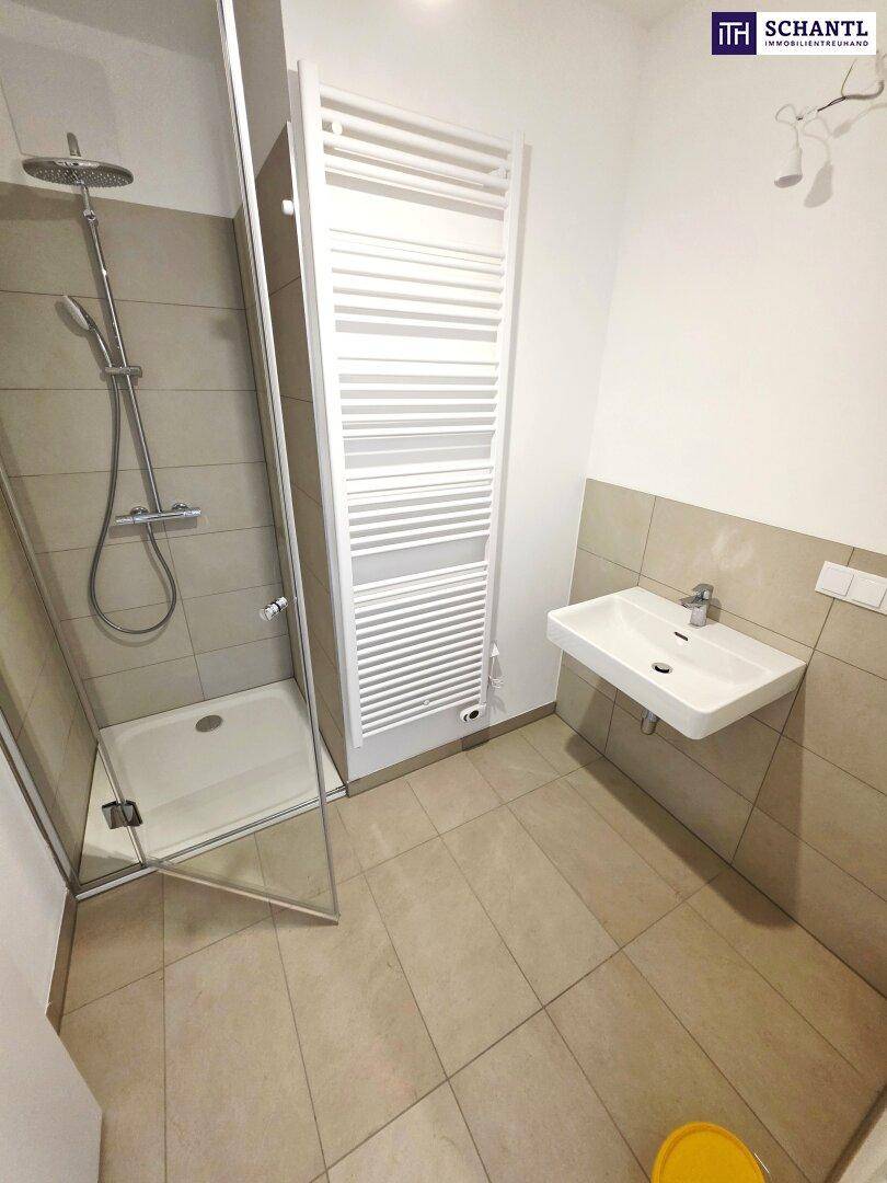 Modernes Badezimmer mit Dusche, Waschbecken, beheiztem Handtuchhalter und Fliesen.