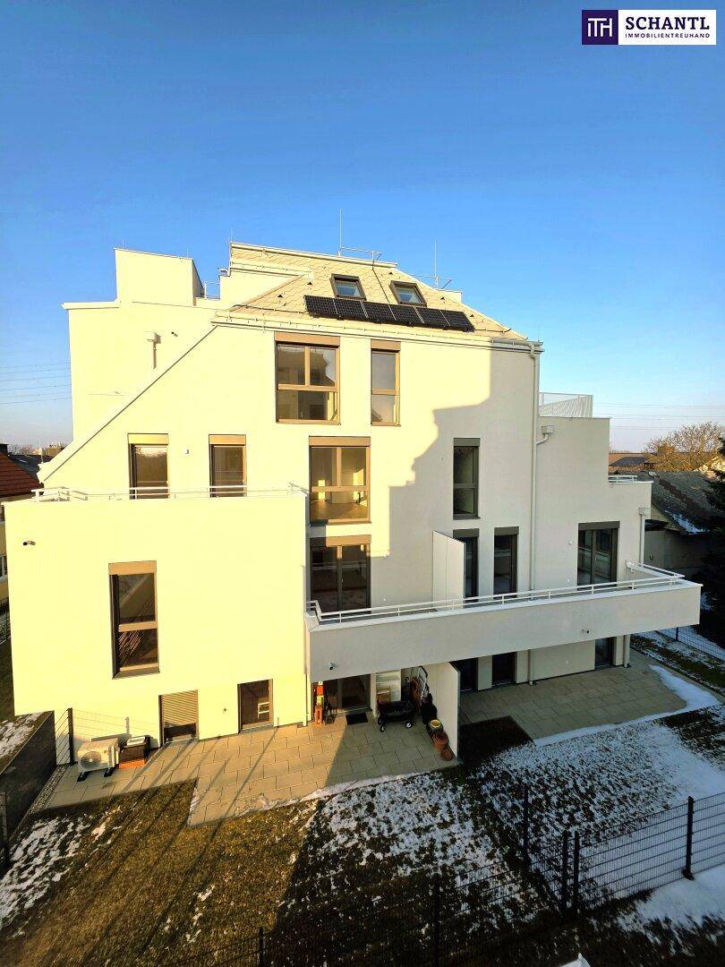 Moderne Wohnanlage mit weißer Fassade, Balkonen und Photovoltaikanlage auf dem Dach.