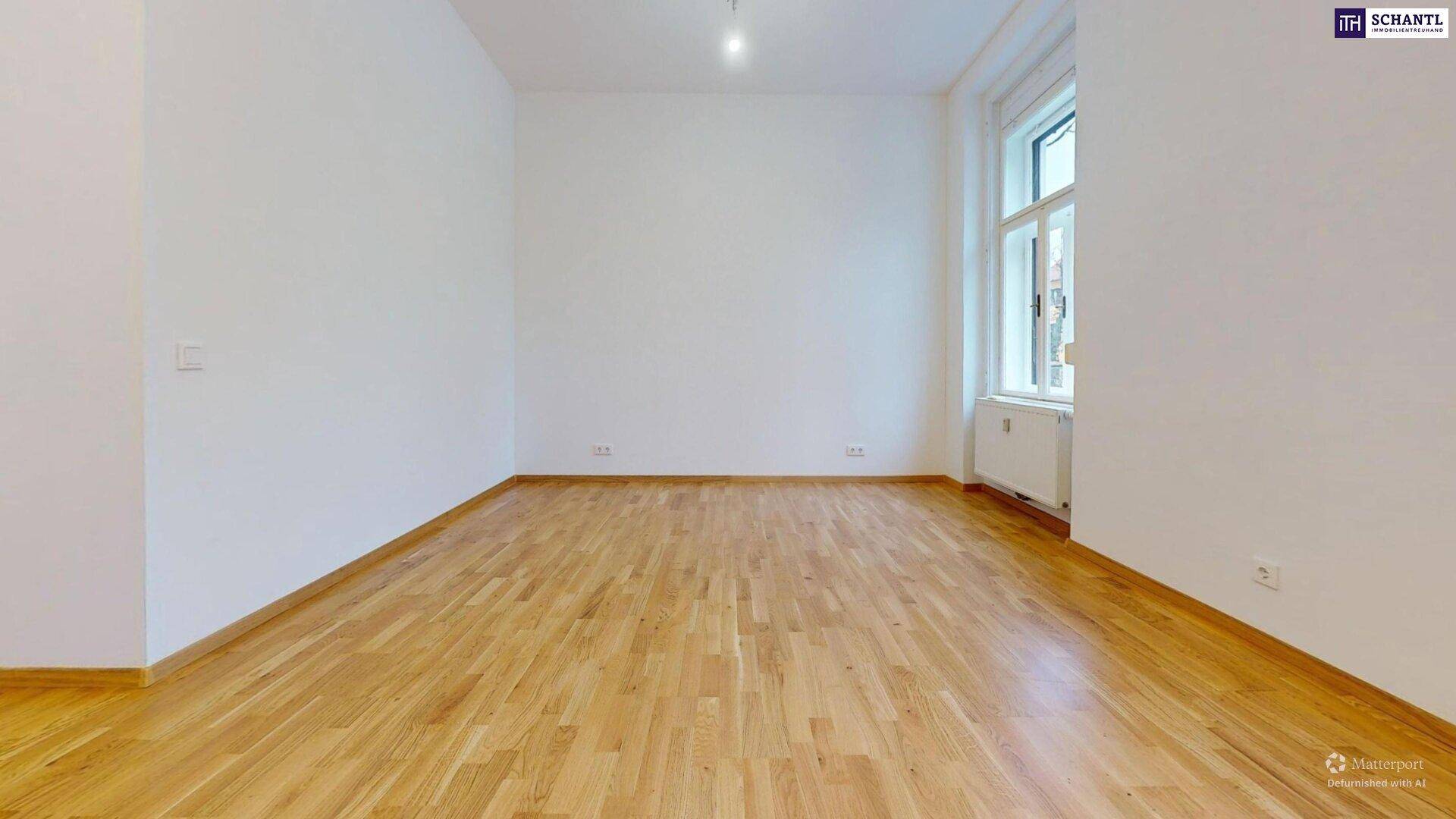 Geräumiges, helles Zimmer mit Holzboden und großem Fenster, ideal als Wohnbereich.