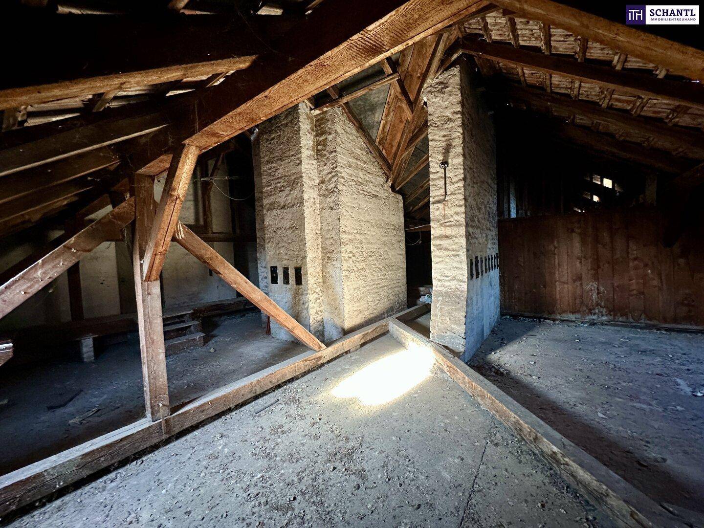Unausgebauter Dachboden mit sichtbaren Holzbalken und gemauerten Schornsteinen, bereit für den Ausbau.