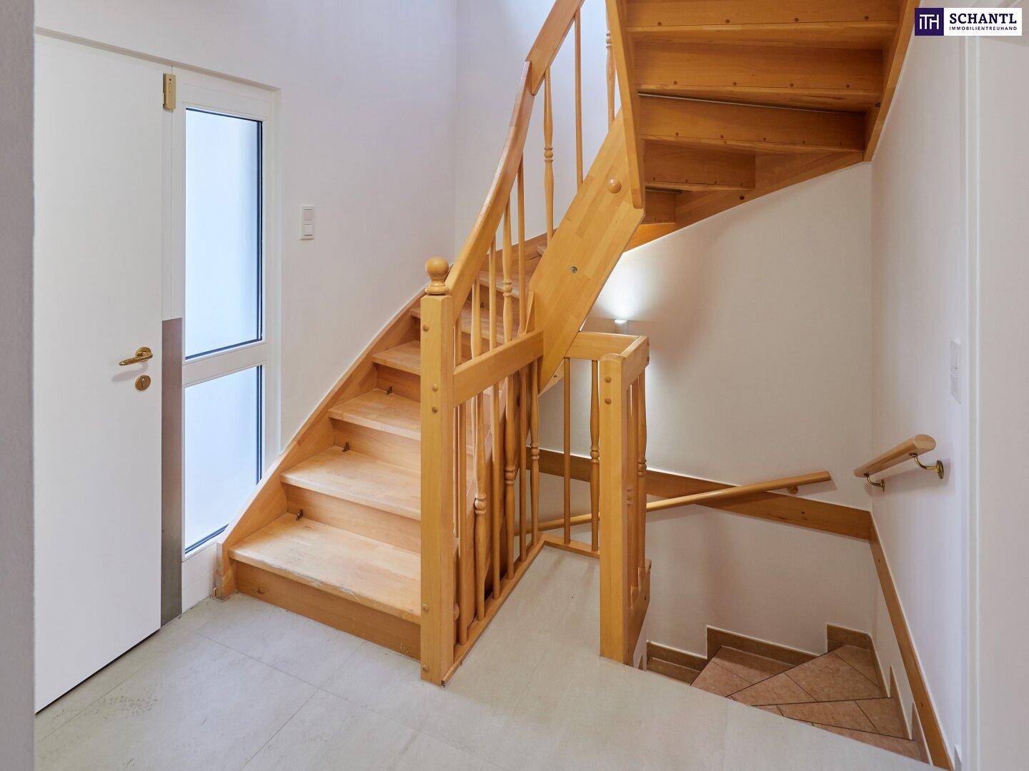 Helles Treppenhaus mit Holztreppe und Geländer, das die verschiedenen Etagen verbindet.