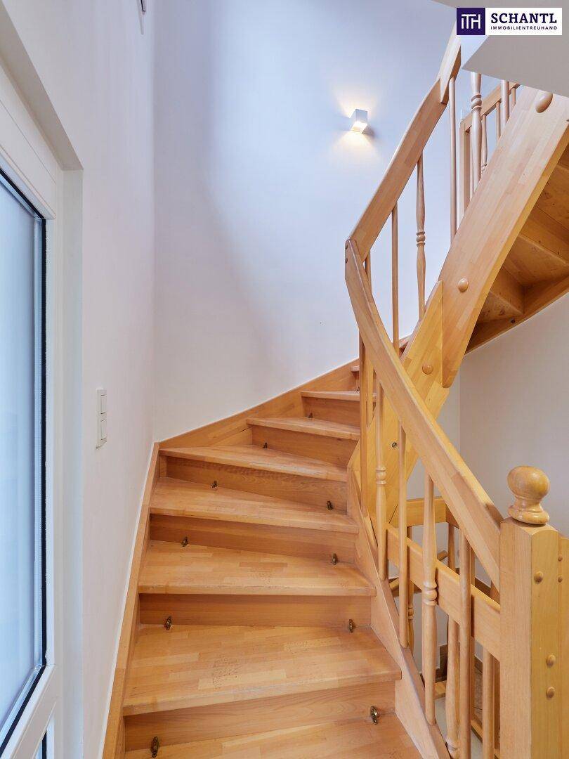 Elegante Holztreppe mit hellem Geländer, die zu den oberen Etagen führt.