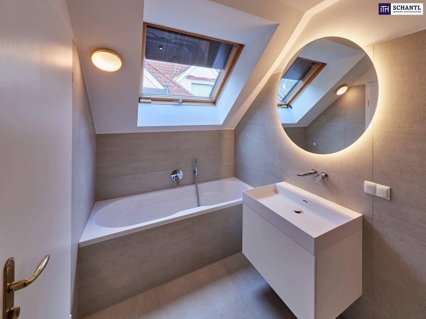 Elegantes Badezimmer mit Badewanne, modernem Waschtisch und Dachfenster für viel Tageslicht.