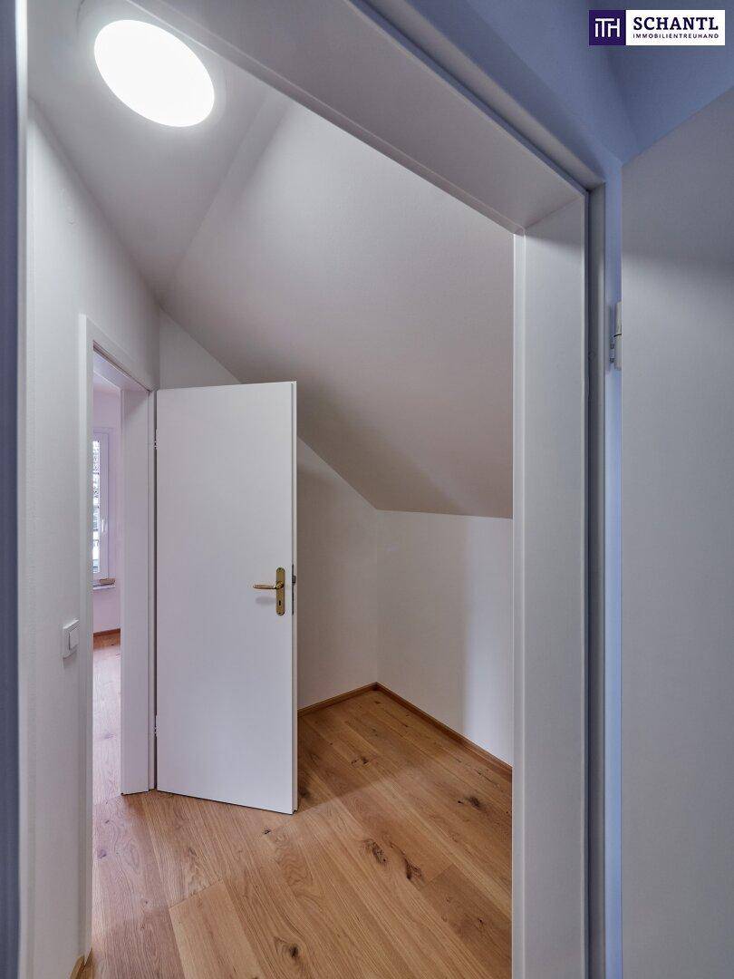 Flur mit Holzboden und Zugang zu einem weiteren Raum, möglicherweise einem Abstellraum.