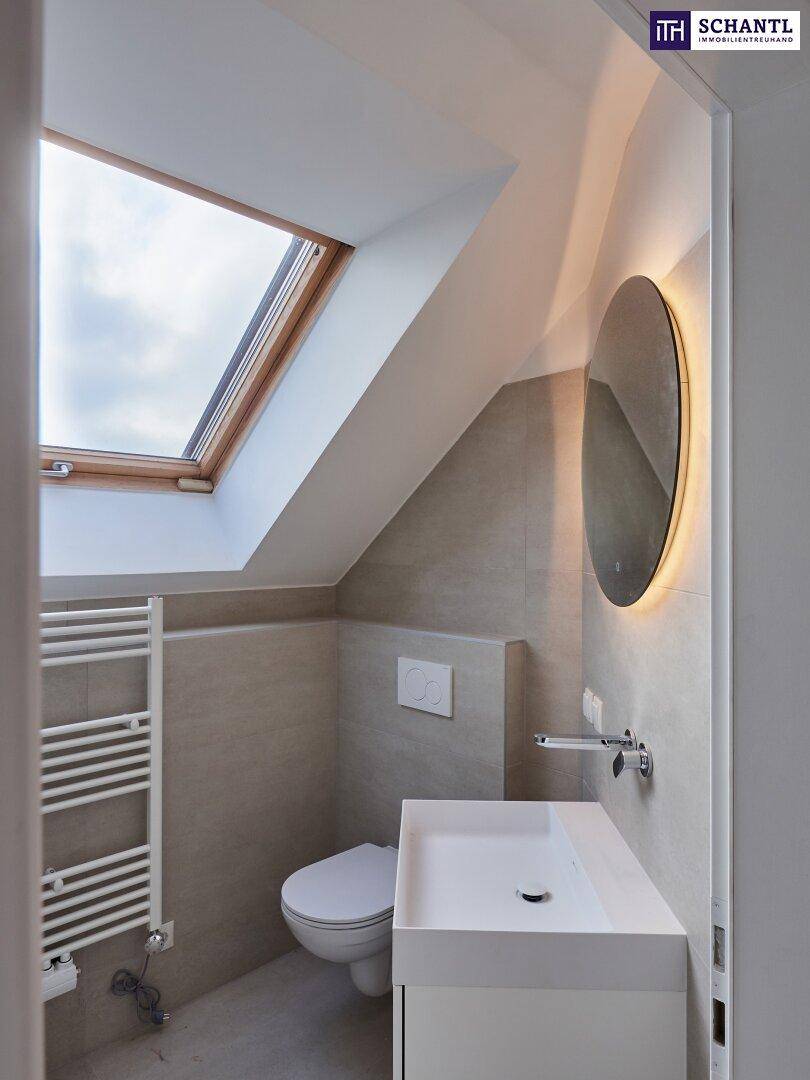 Modernes Badezimmer mit Waschtisch, Wand-WC, beheiztem Handtuchhalter und Dachfenster.