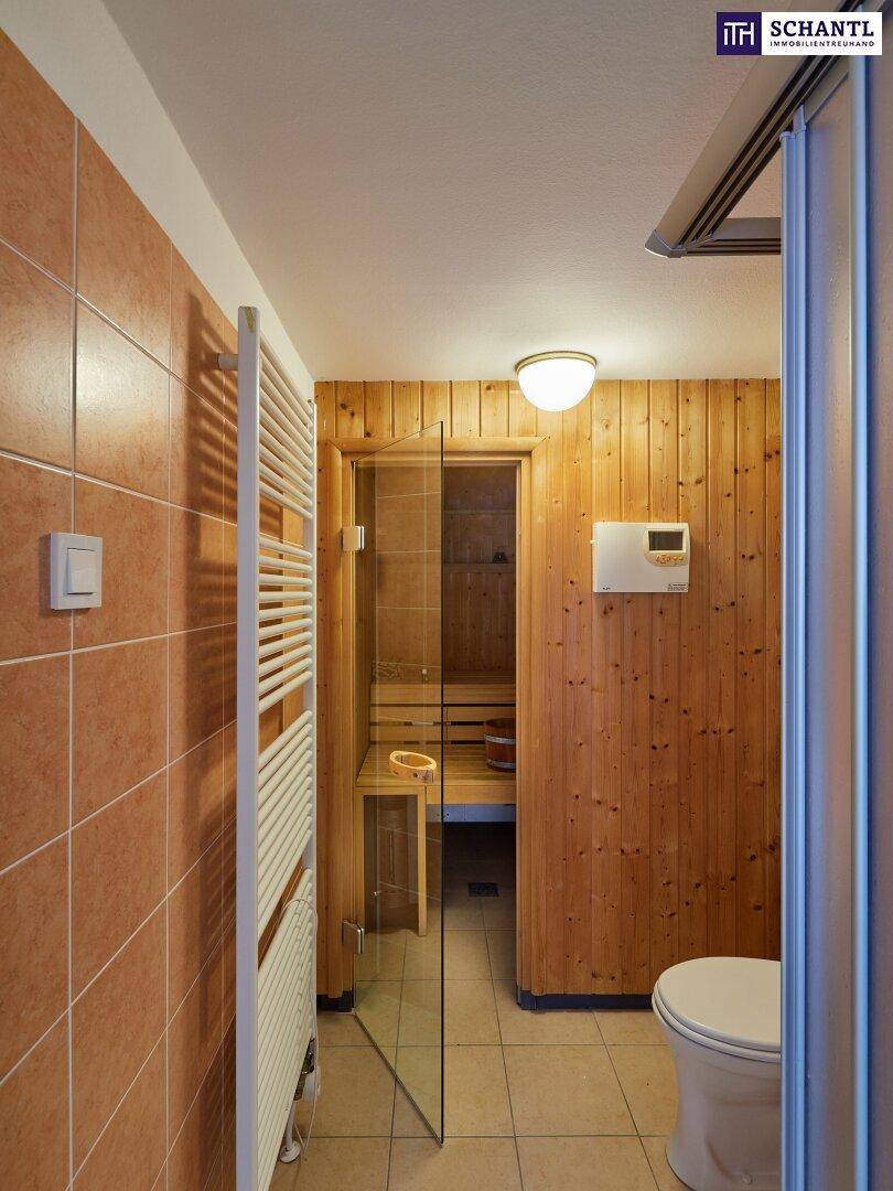 Badezimmer mit Fliesenboden, beheiztem Handtuchhalter und direktem Zugang zu einer Sauna.