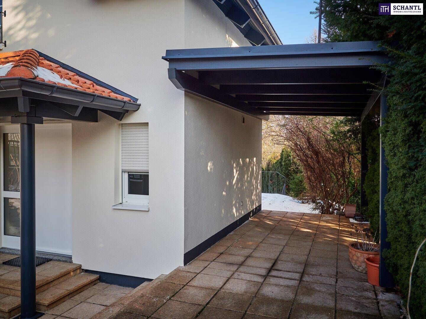 Überdachter Carport-Bereich mit gepflastertem Boden neben dem Haus.