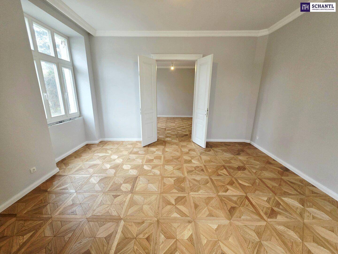 Helles Zimmer mit großen Fenstern, elegantem Parkettboden und hohen Decken, frisch renoviert.