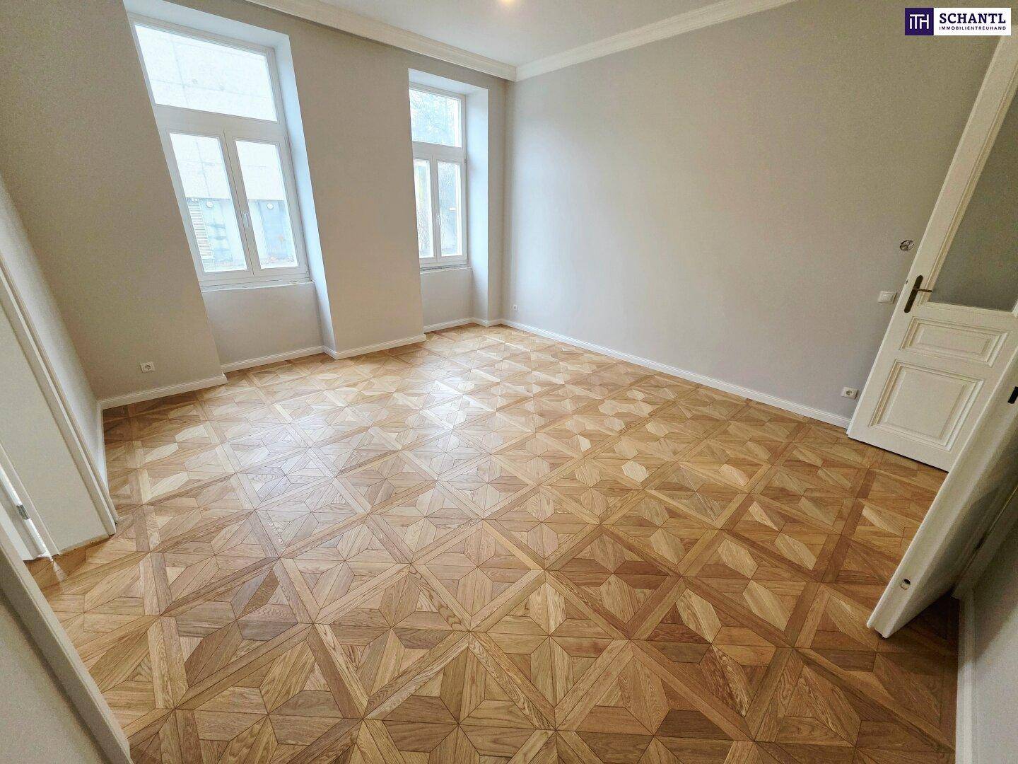 Helles Zimmer mit großen Fenstern, elegantem Parkettboden und hohen Decken, frisch renoviert.