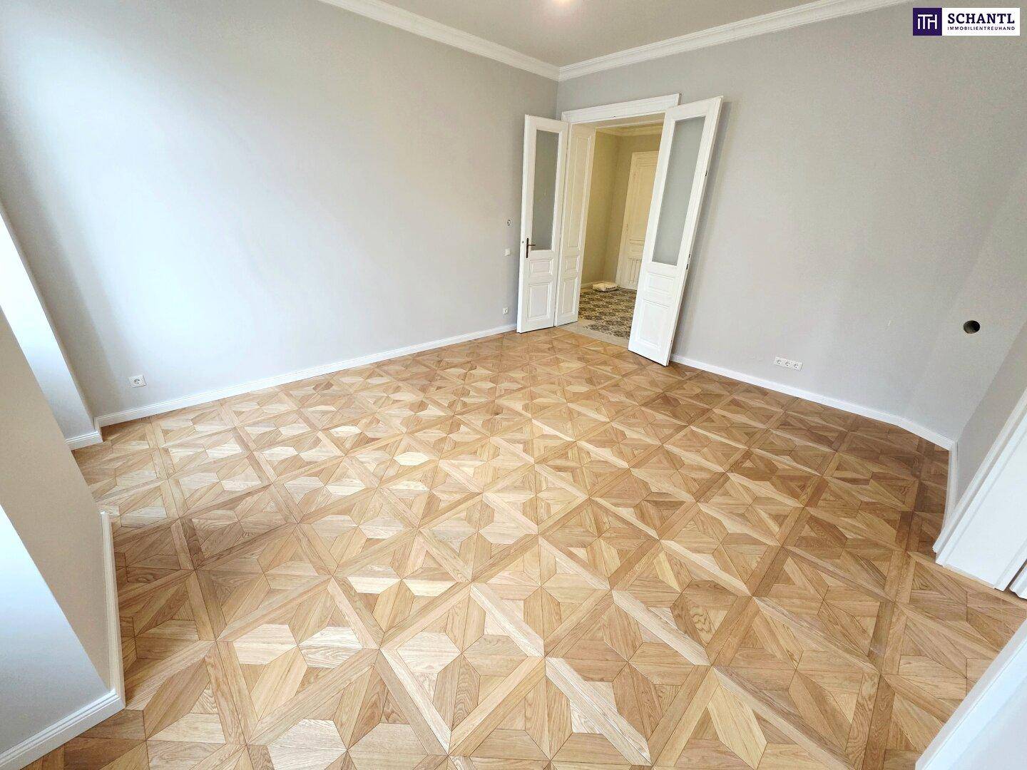 Geräumiges Zimmer mit elegantem Parkettboden und hohen Decken, bereit zur Einrichtung.