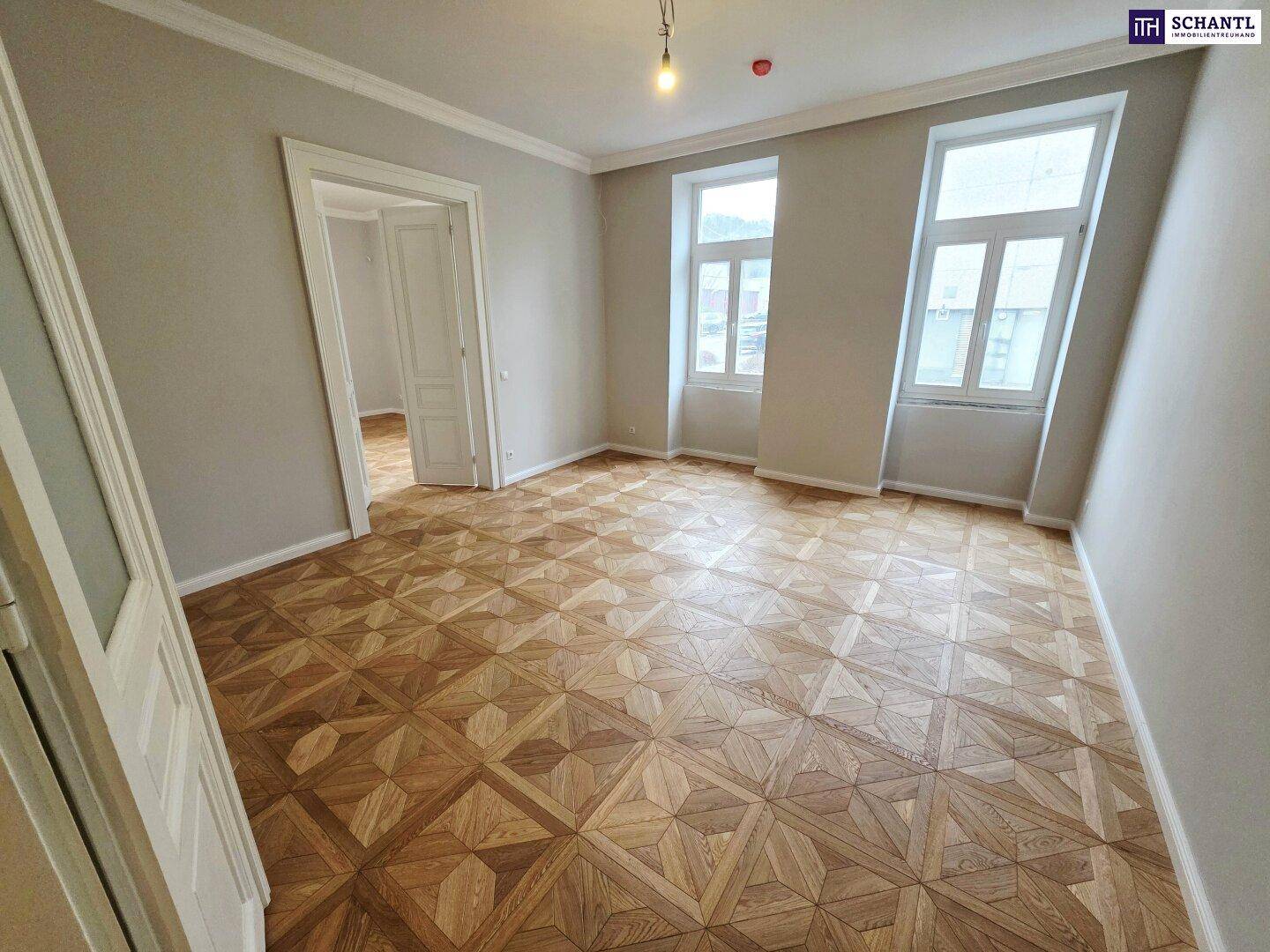 Helles Zimmer mit großen Fenstern, elegantem Parkettboden und hohen Decken, frisch renoviert.