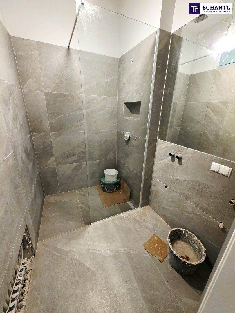 Badezimmer im Umbau mit moderner Duschkabine und grauen Fliesen, bereit zur Fertigstellung.