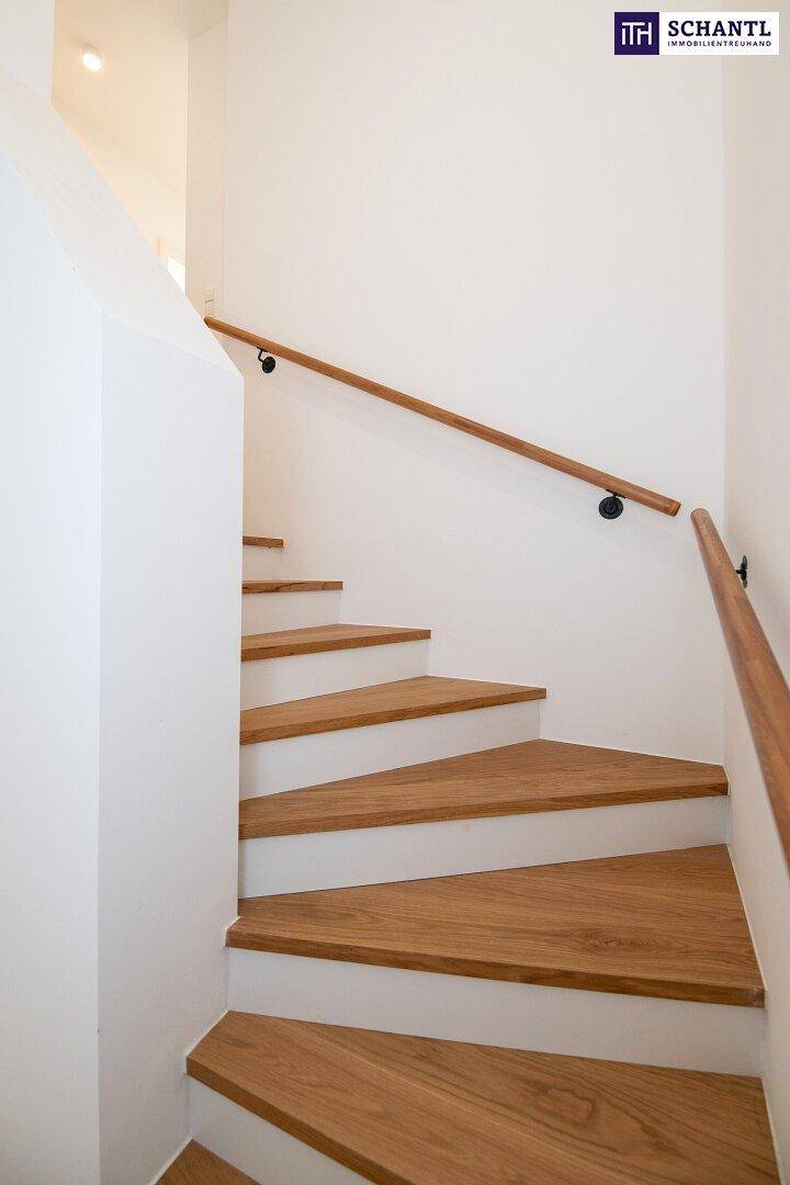Moderne Holztreppe mit schlichtem Handlauf und weißer Wandgestaltung.