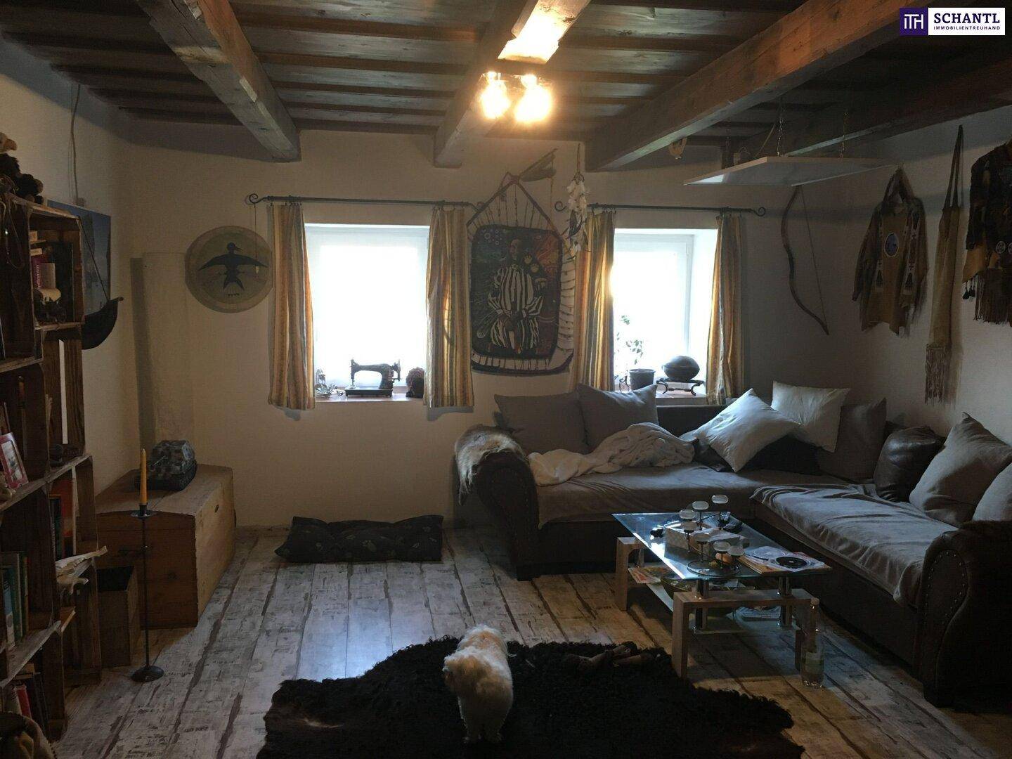 Rustikales Wohnzimmer mit Holzbalkendecke, Holzboden und gemütlicher Sitzecke, die viel Charme bietet.