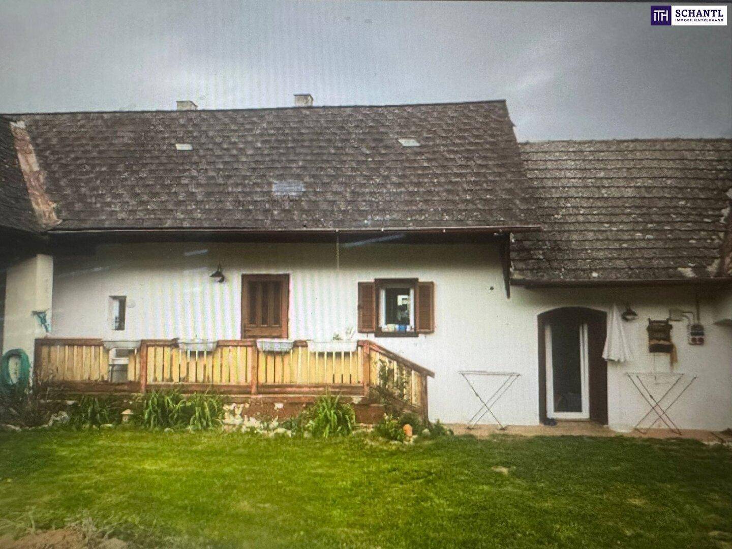 Hölzerne Terrasse am Haus mit Blick auf den Garten und die grüne Umgebung, ideal zum Entspannen.