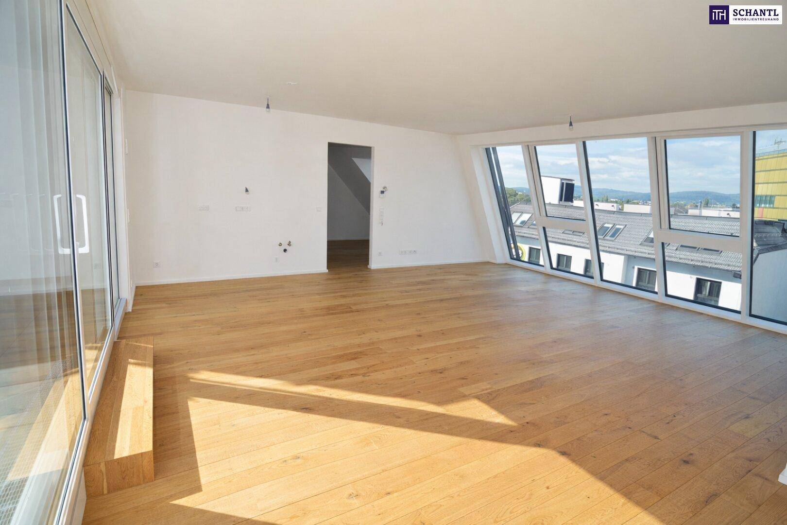 Geräumiger Wohnbereich mit großen Fenstern und Holzboden, ideal für offenes Wohnen.